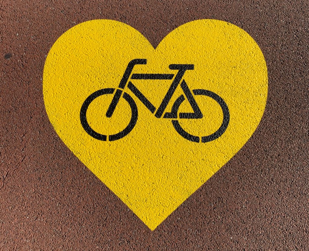 Image of a big yellow heart with a black bike outline drawing from the side painted onto a road.